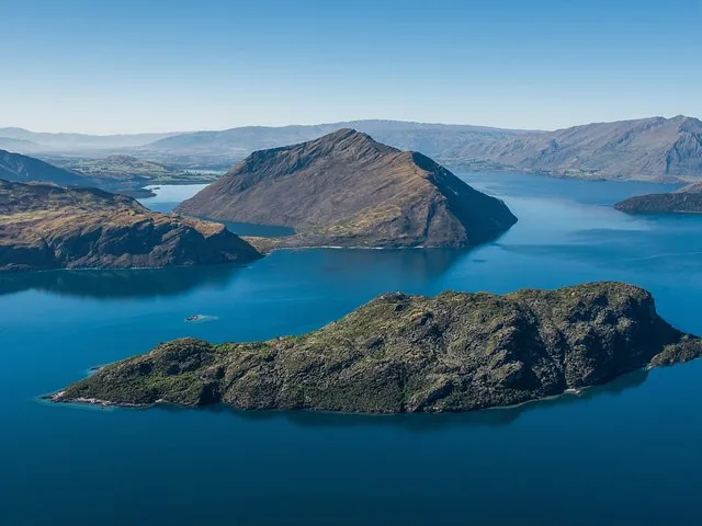 Vista aérea de islas en un sereno lago azul rodeado de montañas.