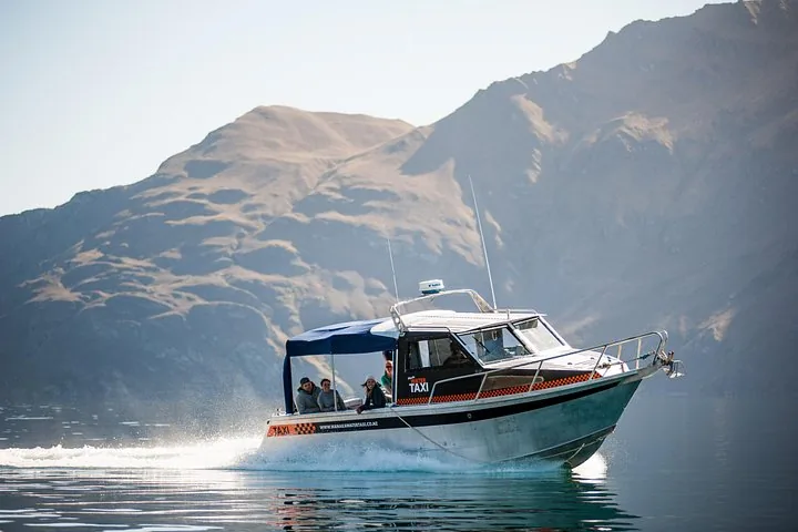 A water taxi speeding across the lake with mountains in the background.