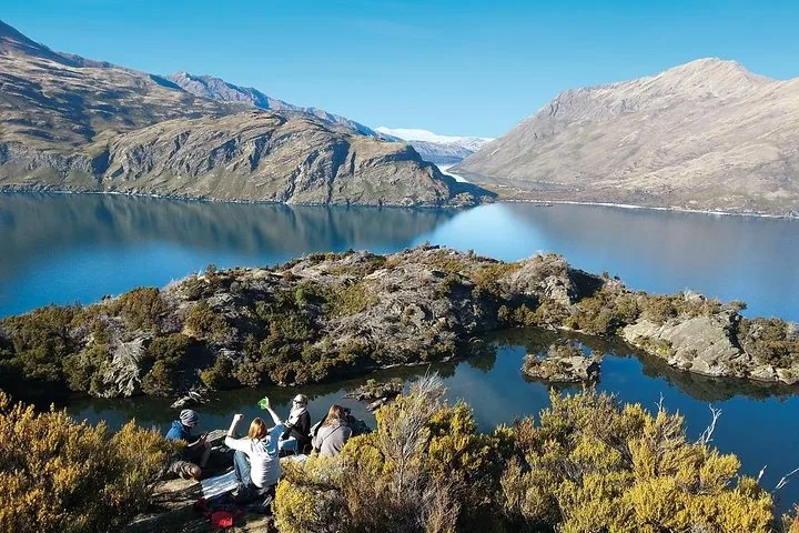 Un groupe d’amis pique-niquant sur un coin rocheux surplombant un beau lac.